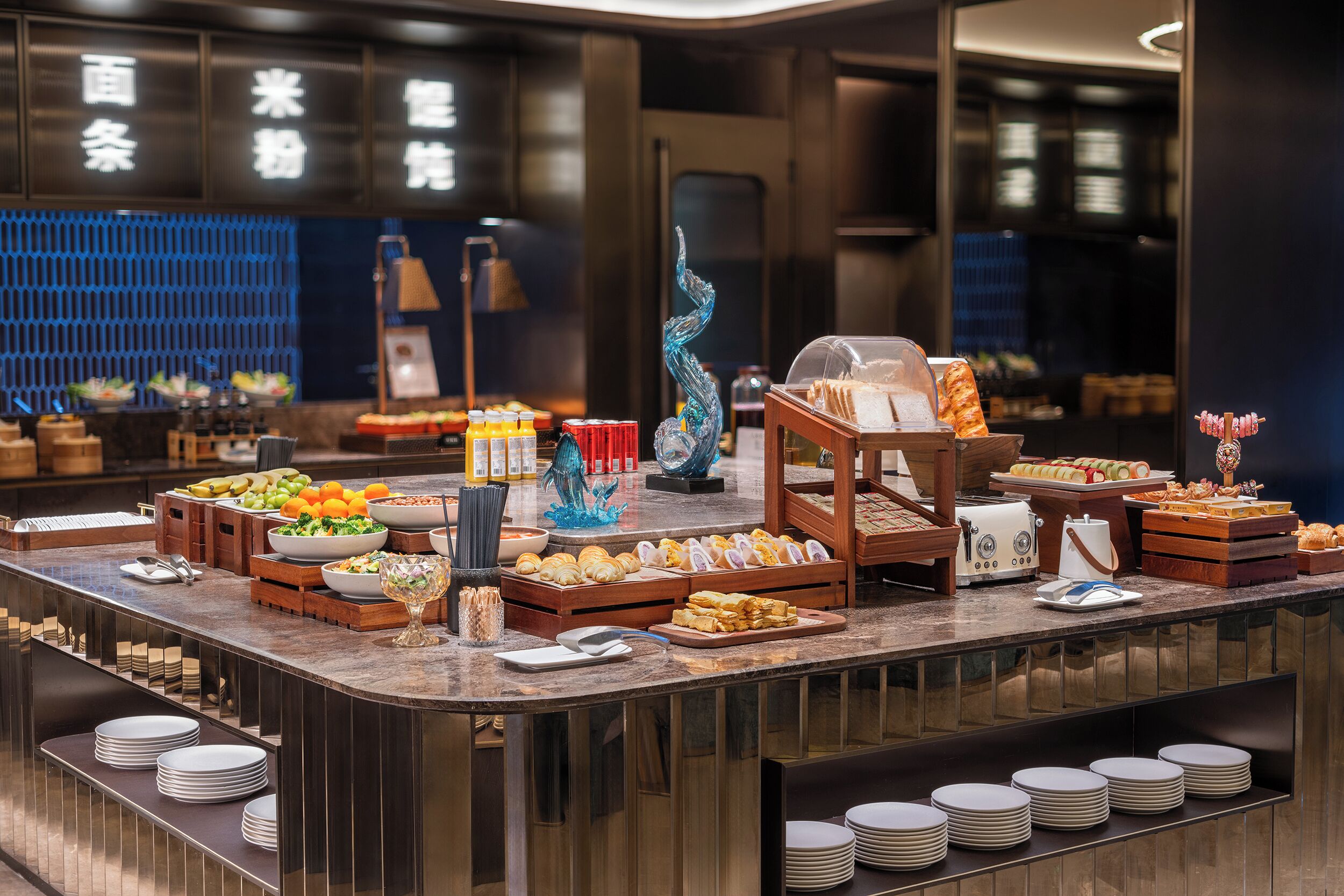 A buffet with various food items and a decorative glass sculpture.