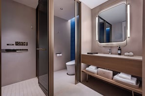 A modern bathroom with a glass shower enclosure, a wooden vanity with a mirror, and a toilet. - Crystal Hotel Qingdao Taidong St. (Qingdao)