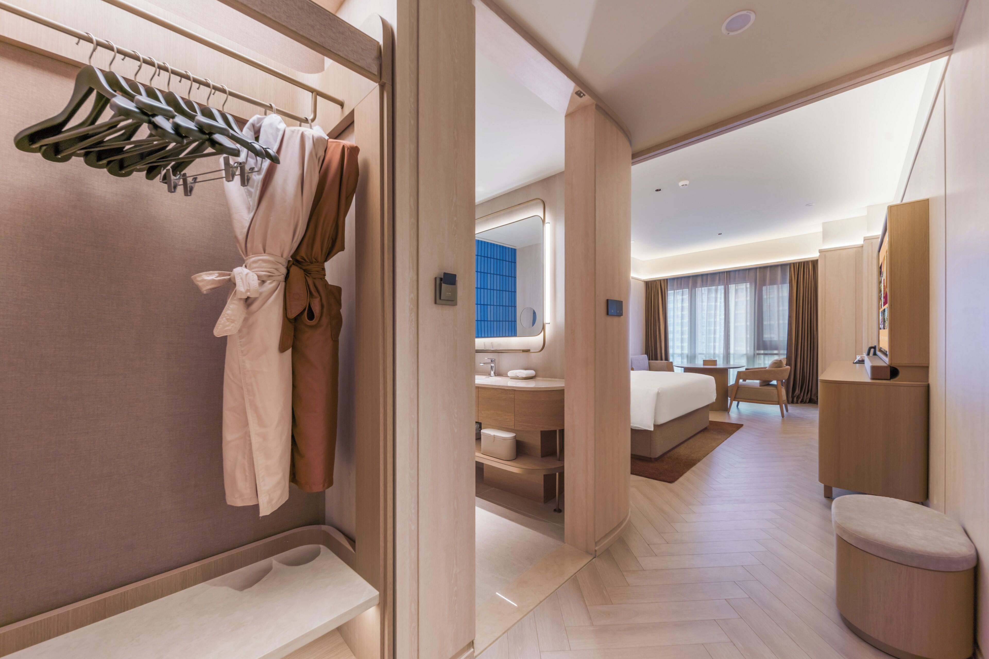 Een hotelkamer met een inloopkast, een groot bed, een badkamer met spiegel en een zithoek.