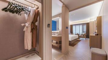 Een hotelkamer met een inloopkast, een groot bed, een badkamer met spiegel en een zithoek.
