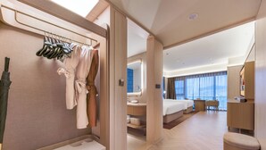 Habitación de hotel moderna con una cama grande, zona de estar, baño y vistas a la ciudad.