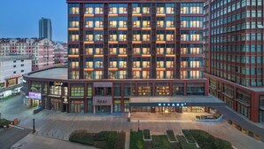 Un hotel de varios pisos con fachada moderna, ventanas amplias y un área de entrada bien iluminada.