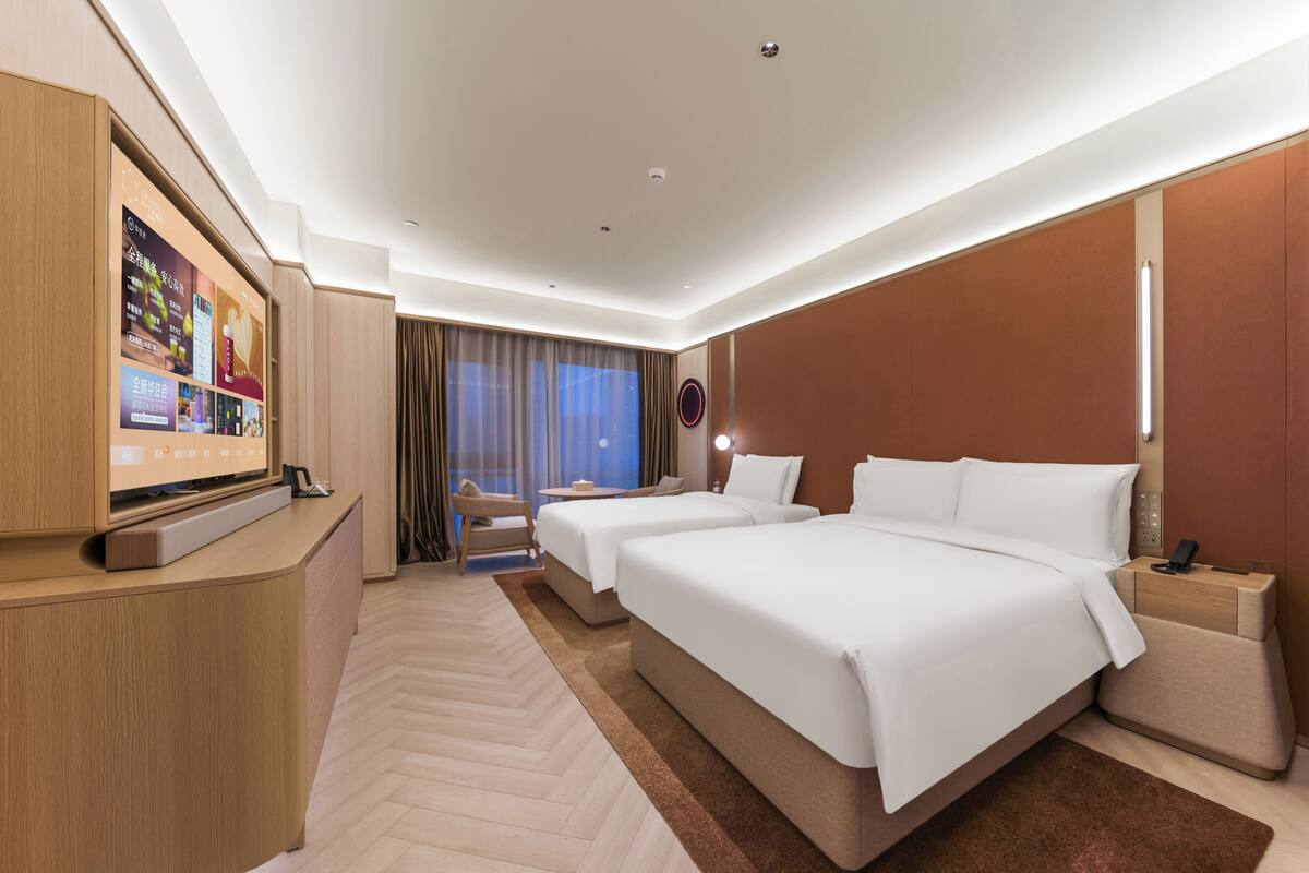 A hotel room with a large bed, a desk, a TV, and a view of the outdoors.