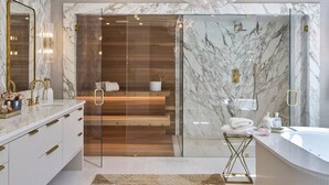 A modern bathroom with a marble wall, a glass shower enclosure, and a large chandelier.