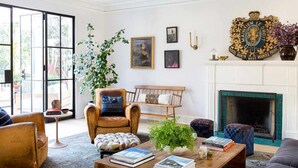A living room with a fireplace, a large window, and a mounted police crest on the wall.