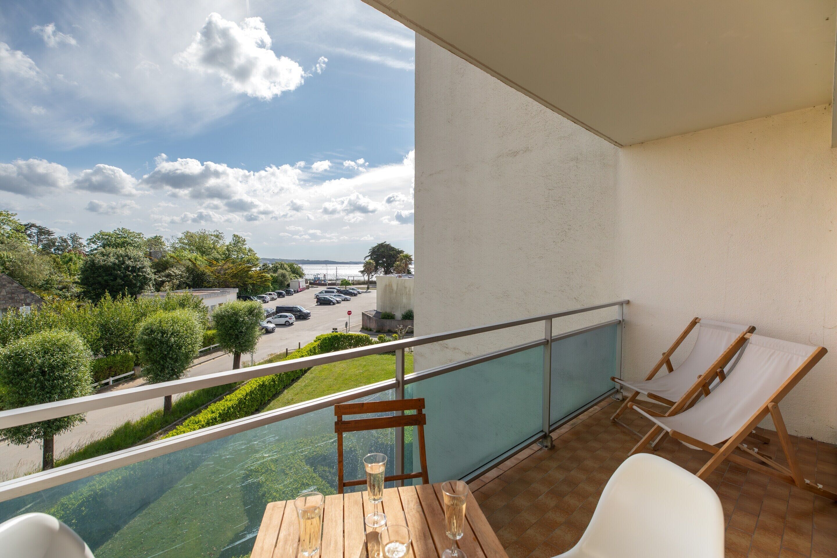 Un balcón con vista a un estacionamiento, una piscina y un cielo despejado.