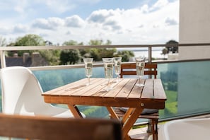 A wooden table with four glasses on a balcony overlooking a pool and greenery. - Apartment 100m From the Beach in Plougonvelin (Plougonvelin)