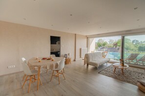 A modern living room with a dining area, a sofa, and a view of the outdoors. - Apartment 100m From the Beach in Plougonvelin (Plougonvelin)