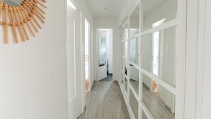 Een gang met witte wanden, een houten vloer en een decoratief object aan de muur.