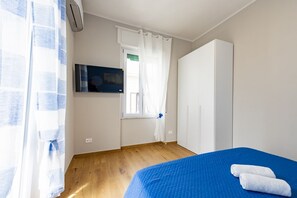 Una camera da letto con un letto, una televisione, un armadio e una finestra con tende.