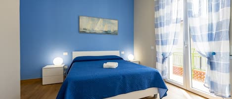 Un dormitorio con una cama, una mesita de noche, una lámpara de pared y un cuadro.