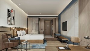 A modern hotel room with a bed, seating area, desk, and artwork on the walls.