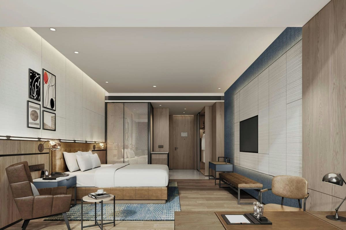 Una habitación de hotel moderna con cama, zona de estar, escritorio y obras de arte en las paredes.