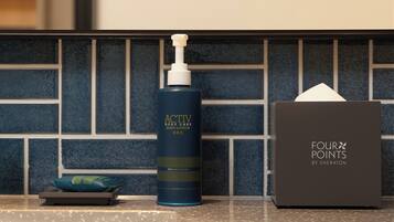 A bathroom counter with a body lotion bottle, a tissue box, and a small bag.