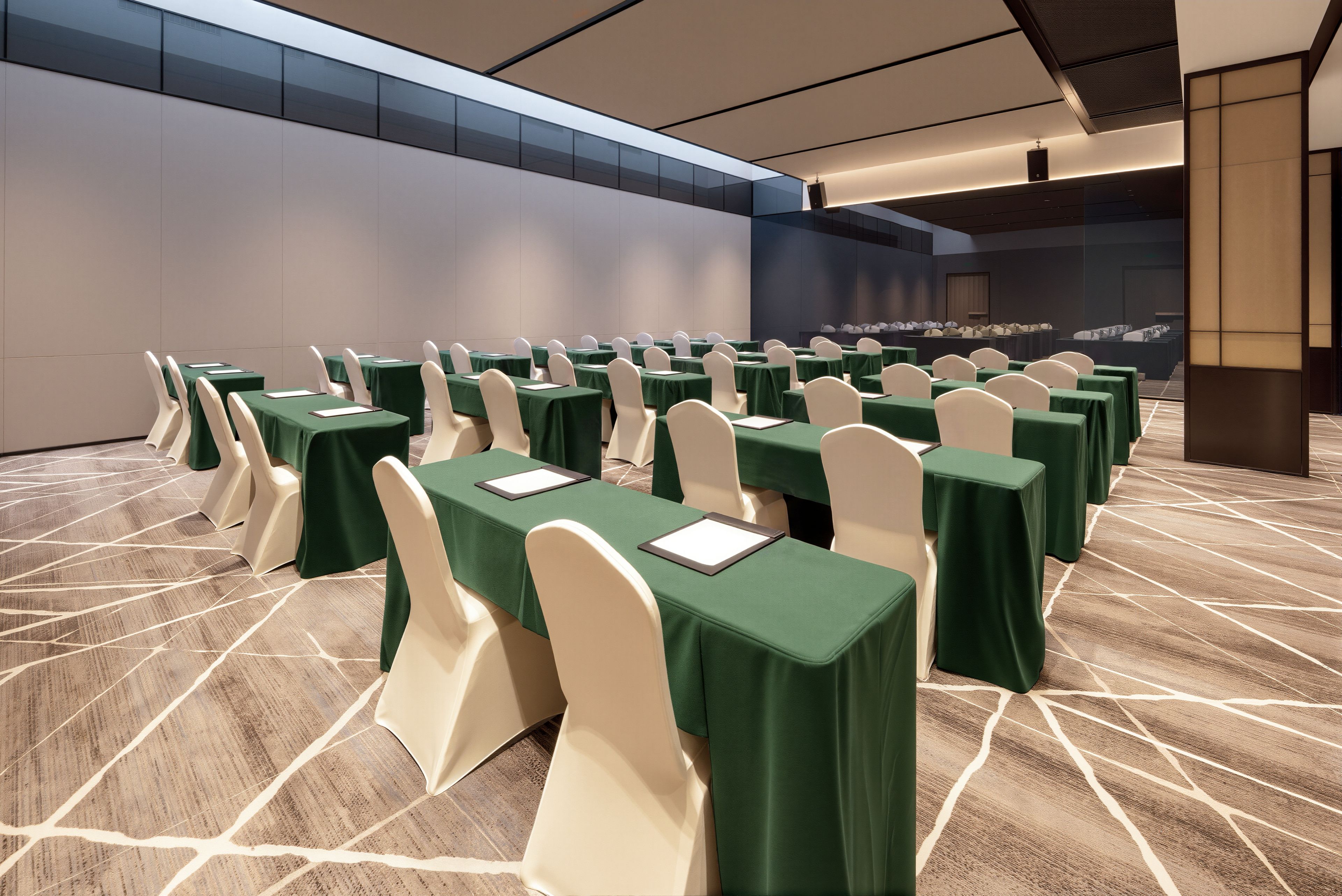 A conference room with rows of tables and chairs, a patterned floor, and a large window.