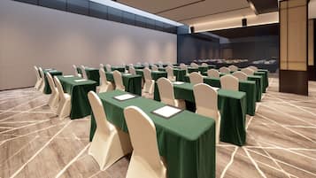 A conference room with rows of tables and chairs, a patterned floor, and a large window.