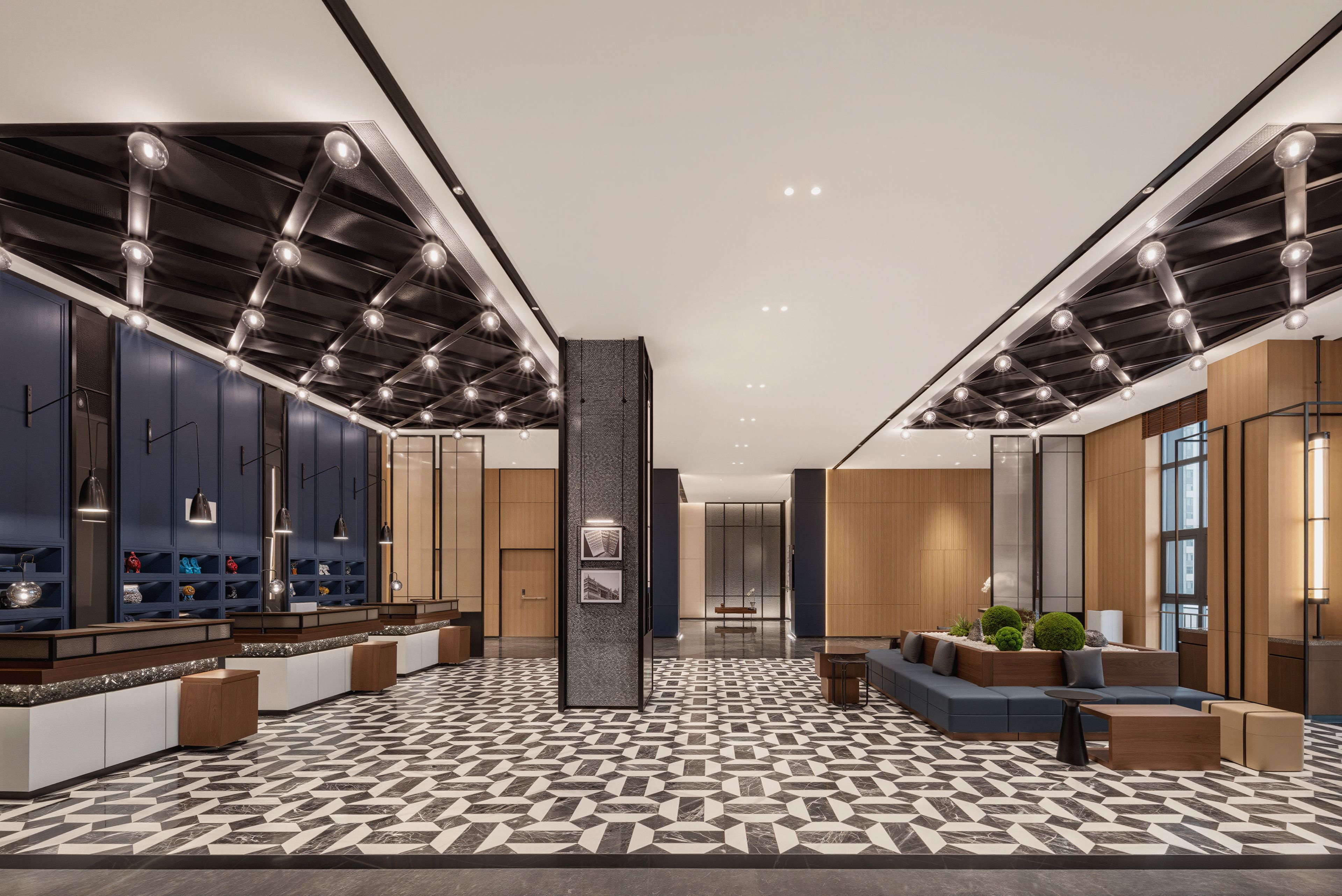 A modern lobby with a geometric patterned floor, a central pillar, and seating areas.