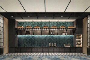 A modern bar area with a herringbone tile backsplash, built-in shelves, and a checkered floor pattern.