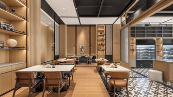 A modern restaurant interior with wooden paneling, multiple dining tables, and a patterned floor.