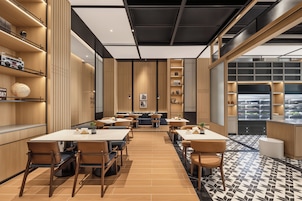 Un interior de restaurante moderno con paneles de madera, varias mesas para comer y un suelo con diseño.