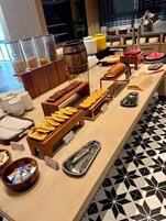 Montaje de bufé con diferentes alimentos, utensilios de servicio y recipientes.