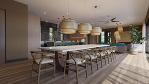 Una cocina moderna con una isla central, iluminación colgante y un comedor con sillas.