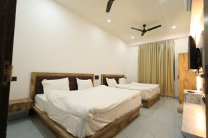 A hotel room with two beds, a ceiling fan, a wooden nightstand, a marble bathroom counter, and a television. - Hotel Vinayak Vista (Khatoo)