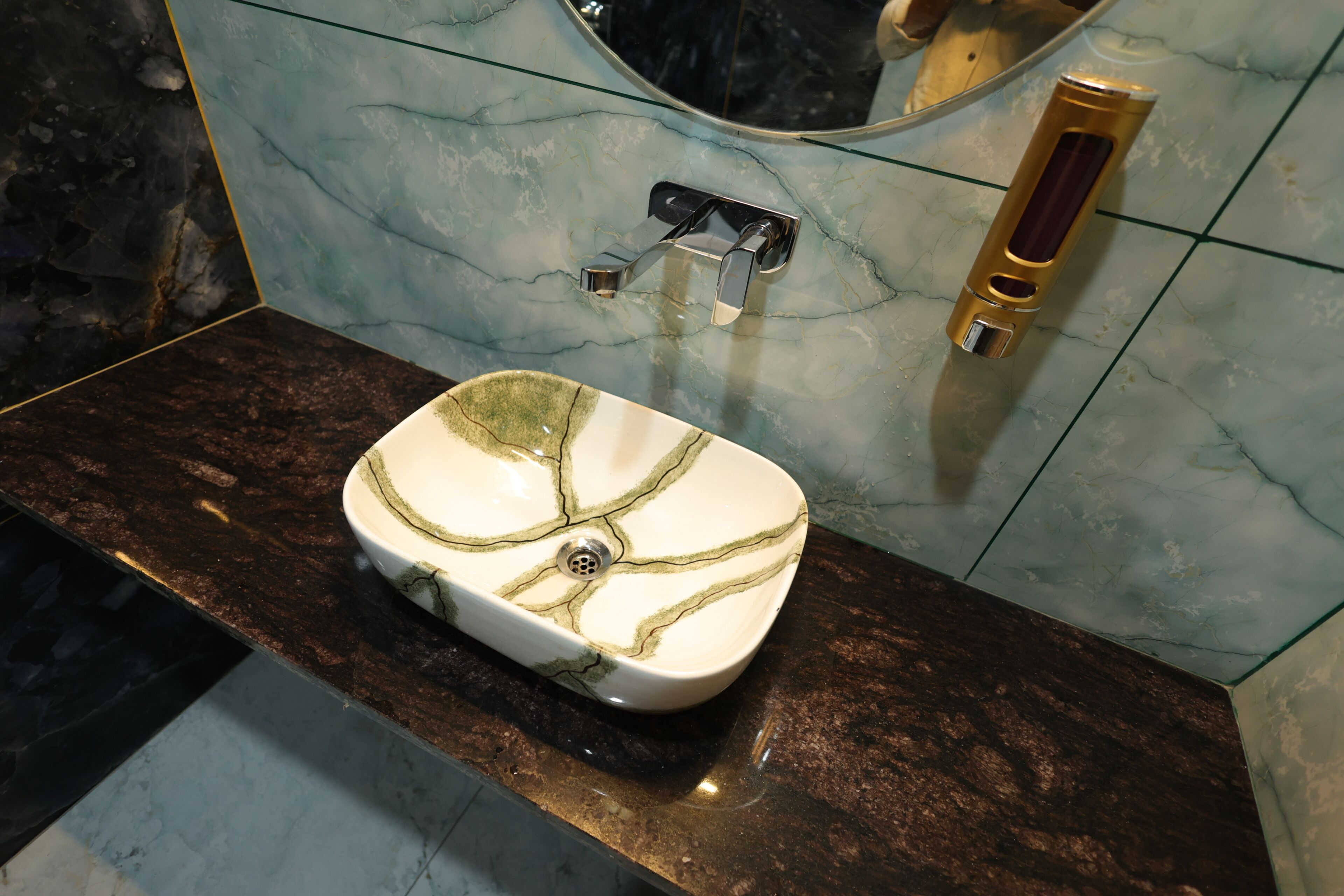 A bathroom with a marble sink, a faucet, and a soap dispenser.