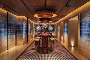 A modern interior with a central round table, bar stools, and a patterned floor.