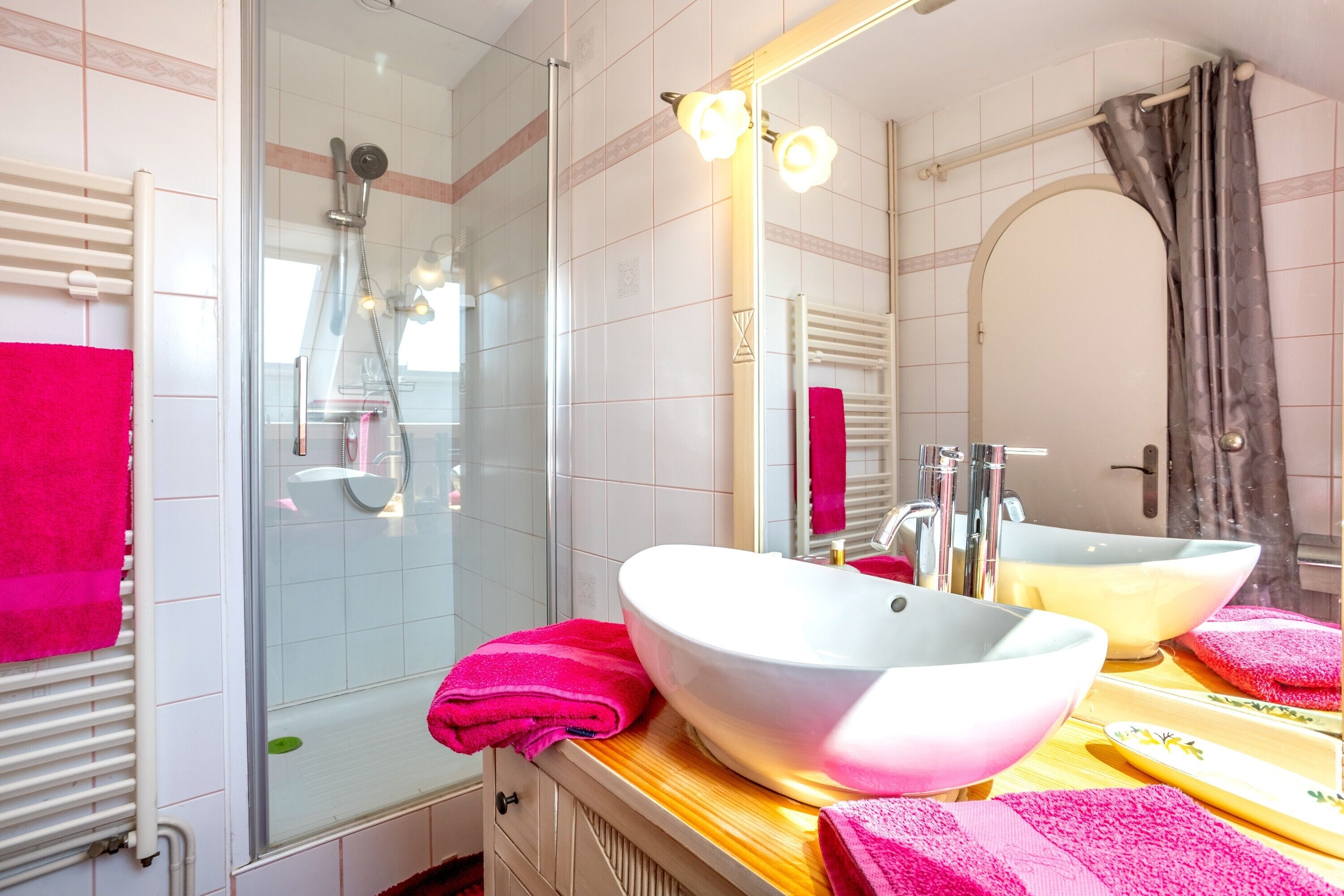 A bathroom with a glass shower enclosure, a white sink, and a mirror reflecting the room.