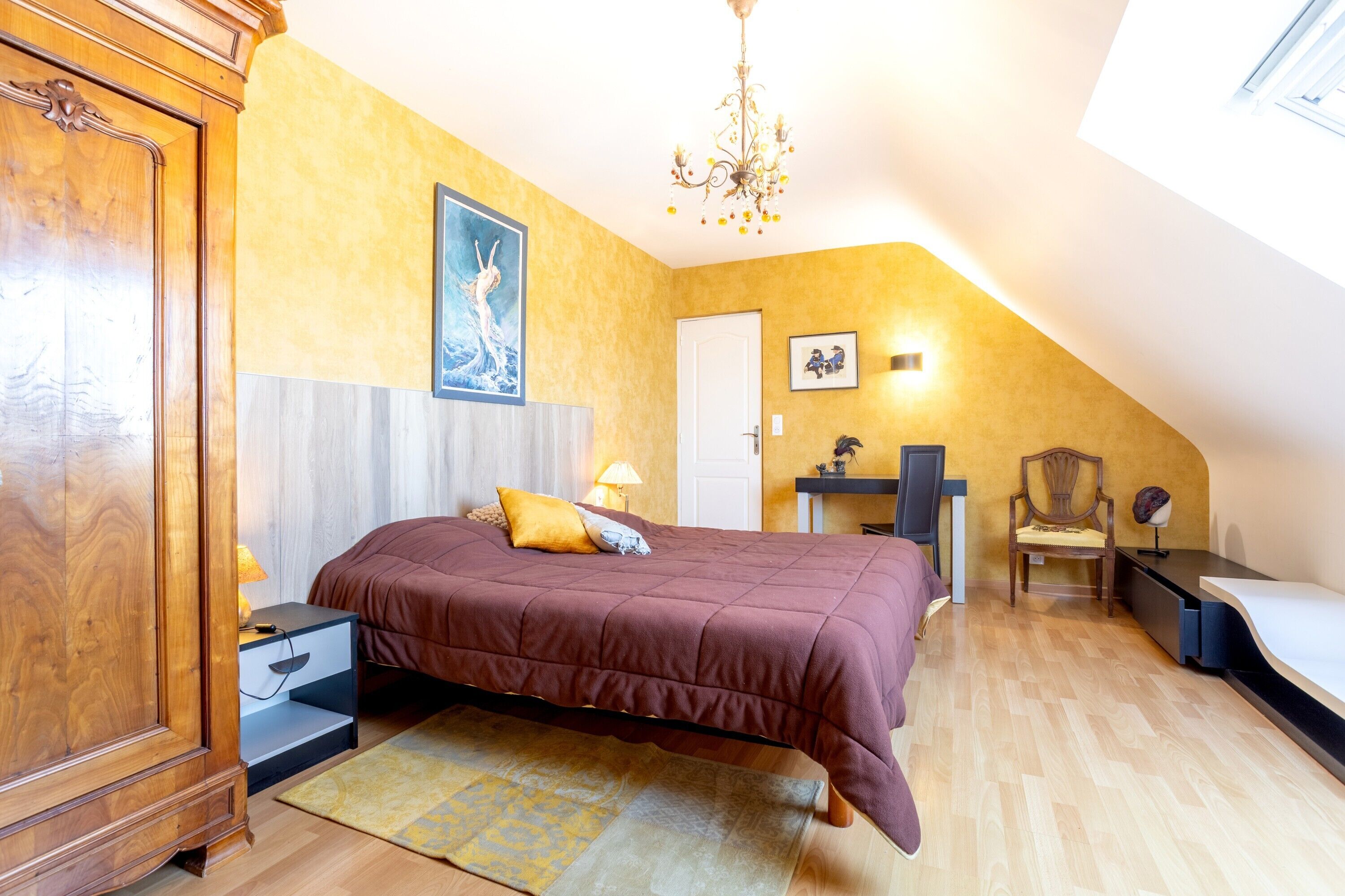 A bedroom with a bed, nightstand, dresser, and a desk with a chair.