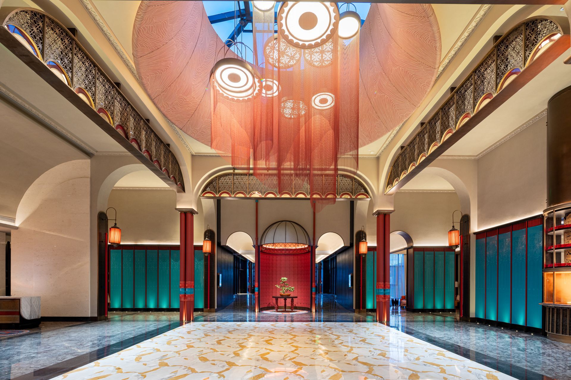Eine geräumige Lobby mit hoher Decke, aufwendiger Deckenverzierungen und einer zentral gelegenen roten Sitzecke.