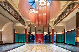 A spacious lobby with a high ceiling, ornate ceiling design, and a central red seating area.