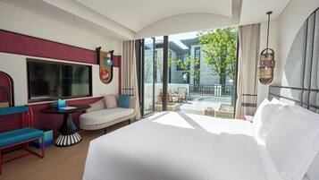 A hotel room with a large bed, a seating area with a table, and a view of the outside.