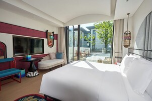 A hotel room with a large bed, a seating area with a table, and a view of the outside.