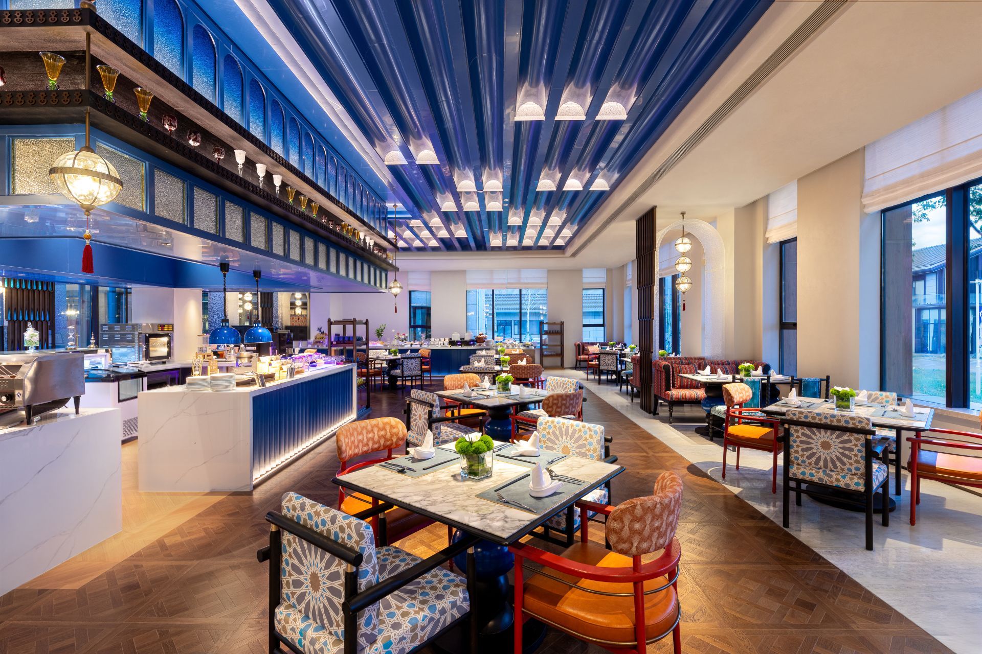 Ein modernes Restaurant mit hoher Decke, mehreren Essbereichen und einer Bar.