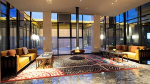 En moderne lobby med et centralt ildsted, behagelige siddepladser og store vinduer.