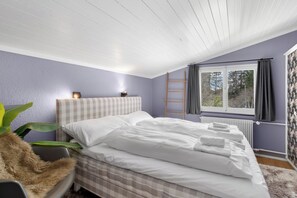 Een slaapkamer met een bed, een raam met gordijnen, een radiator en een plant.
