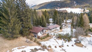 A residential area with houses surrounded by dense forests and mountains in the background.