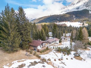 A residential area with houses surrounded by dense forests and mountains in the background.