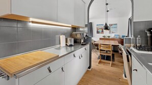 A modern kitchen with grey cabinets, a wooden countertop, and a dining area with a wooden table and chairs.