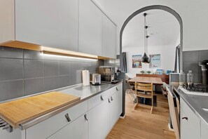 A modern kitchen with grey cabinets, a wooden countertop, and a dining area with a wooden table and chairs.