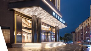 A modern hotel entrance with illuminated signage, large pillars, and a glass facade.