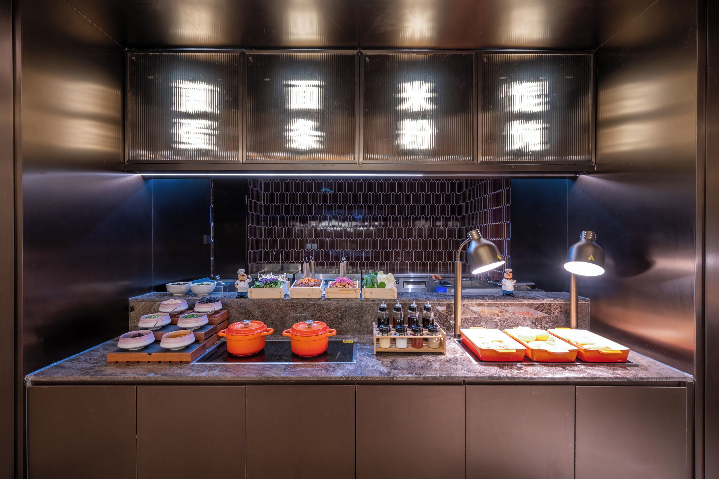 Un piano di lavoro in cucina con diversi utensili e elettrodomestici, una selezione di alimenti e una persona sullo sfondo.
