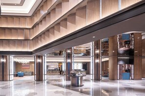 A spacious lobby with a high ceiling, a central reception desk, and a seating area with sofas.