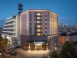 A hotel with a modern design, featuring a prominent entrance with a staircase, multiple floors, and a visible tower structure in the background.
