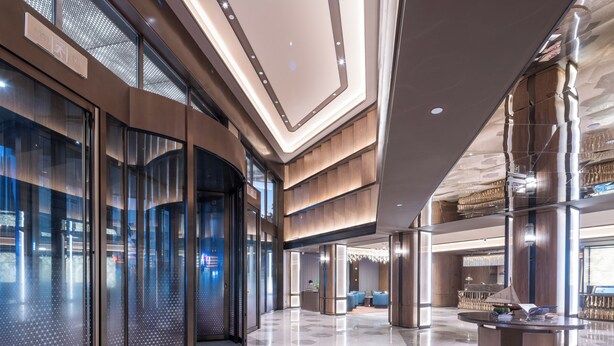 A modern lobby with glass doors, a reception desk, and seating areas.