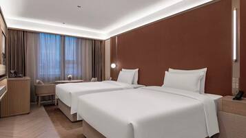 A hotel room with two beds, a desk, a chair, a nightstand, and a large window with curtains.