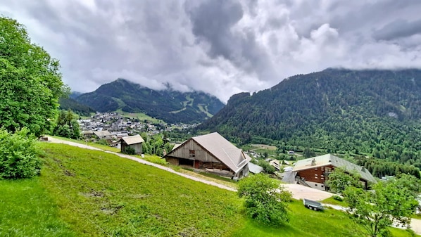 Ein ländliches Dorf mit traditionellen Holzhäusern, einer kurvenreichen Straße und Bergen im Hintergrund.