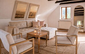 Un salon chaleureux avec un canapé, deux fauteuils, une table basse et des œuvres d’art accrochées au mur.